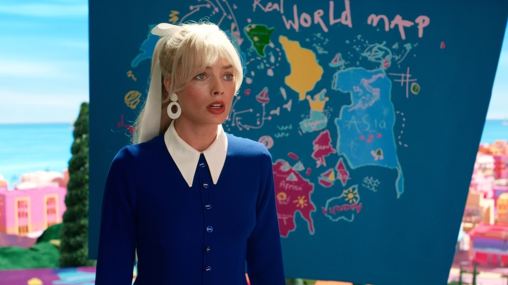Shot from 2023 'Barbie' movie, showing unrealistic 'Real World Map' with various squiggles and dotted lines, including one with 8 dashes near a blob labeled 'Asia'